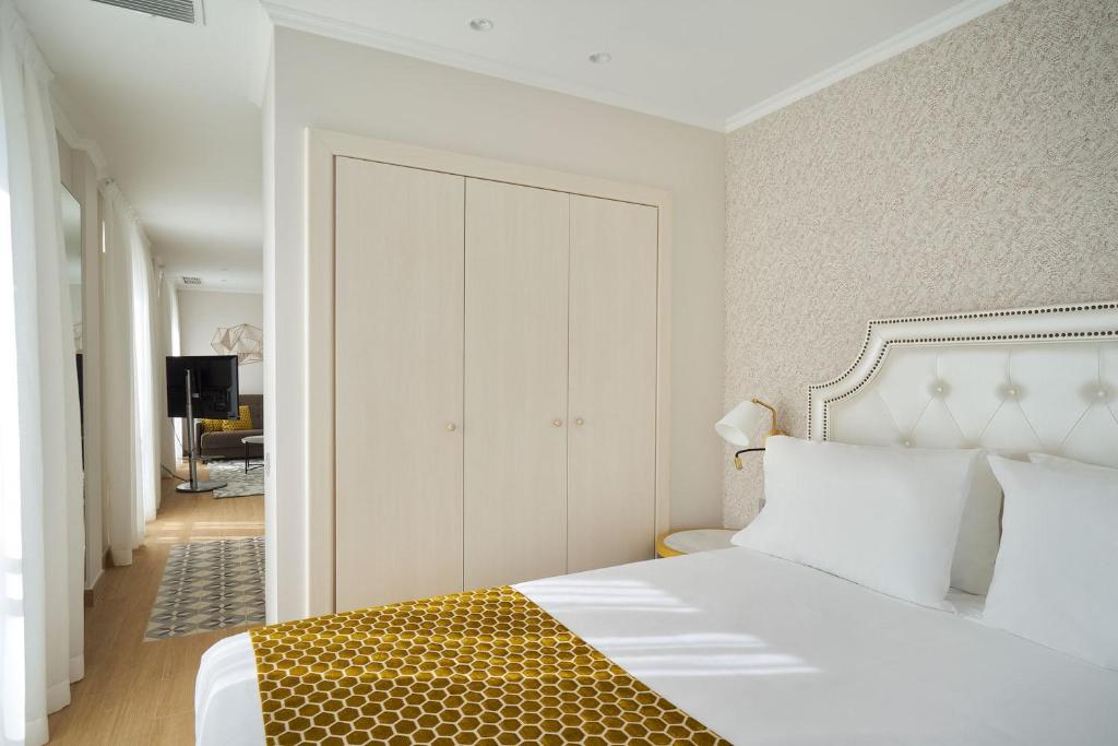 a bedroom with a white bed with a yellow blanket at Tandem Soho Suites in Málaga