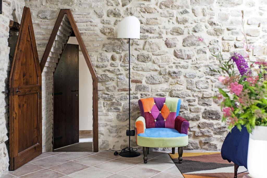 a colorful chair in a room with a stone wall at Agriturismo La Palazzetta di Assisi in Assisi