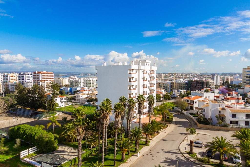 una ciudad con palmeras y un edificio blanco alto en Mirachoro Portimao, en Portimão