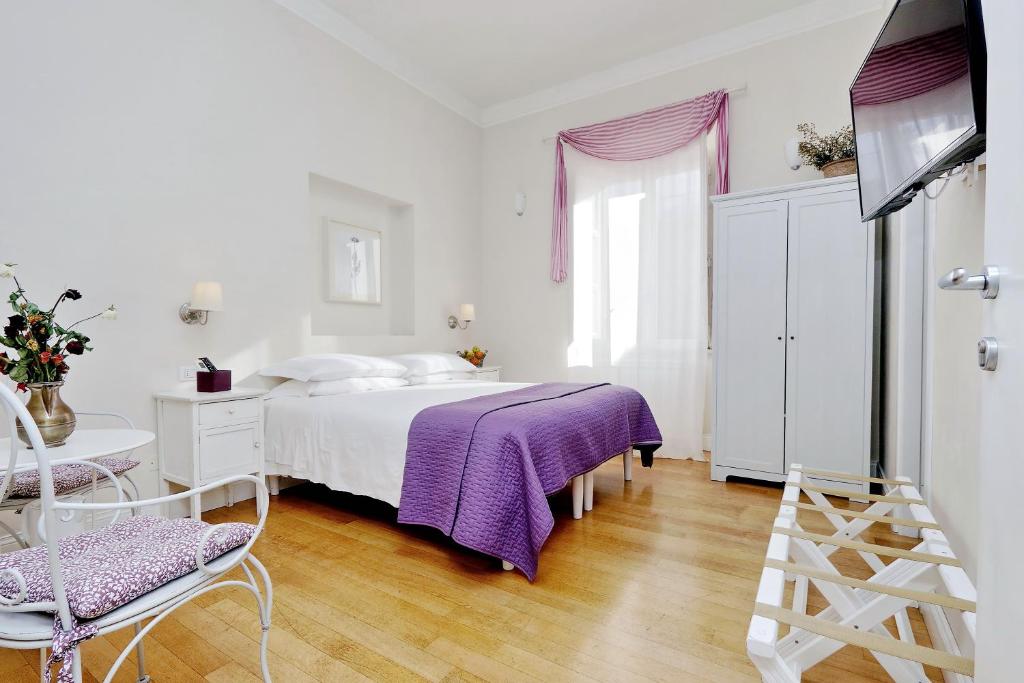 Dormitorio blanco con cama y manta morada en Guest House Amaranto Romano en Roma