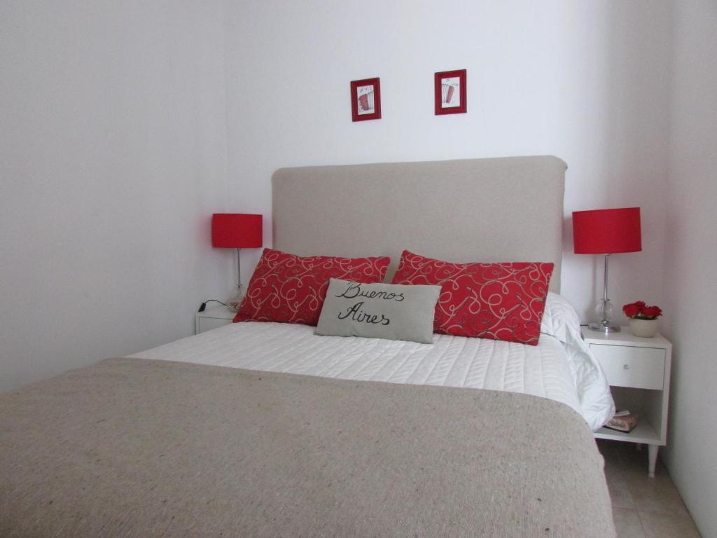 um quarto com uma cama com almofadas vermelhas e 2 candeeiros em Departamento Tango & Resto-Hospital Ital y Sanatorio Güemes em Buenos Aires