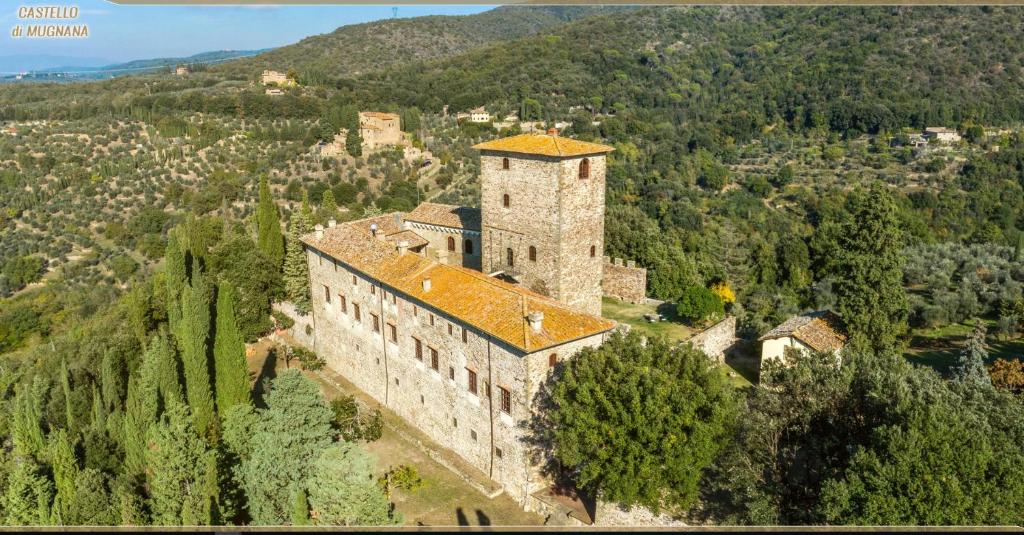 un antiguo edificio en la cima de una colina con árboles en Castello di Mugnana, en Mugnana