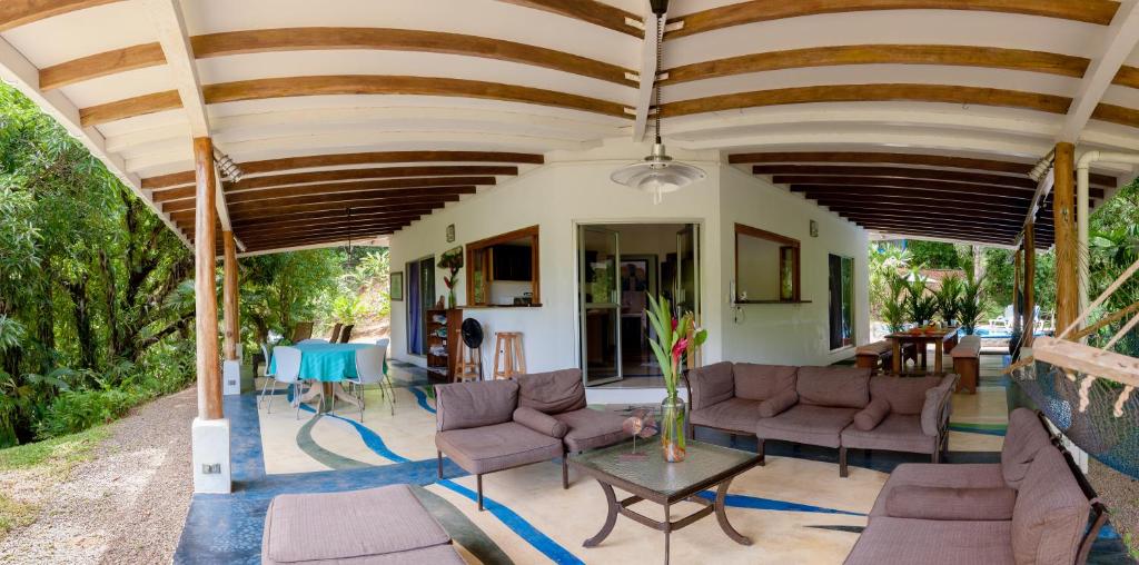 a covered patio with couches and a table at Casa Cedro - Portasol Vacation Rentals in Matapalo