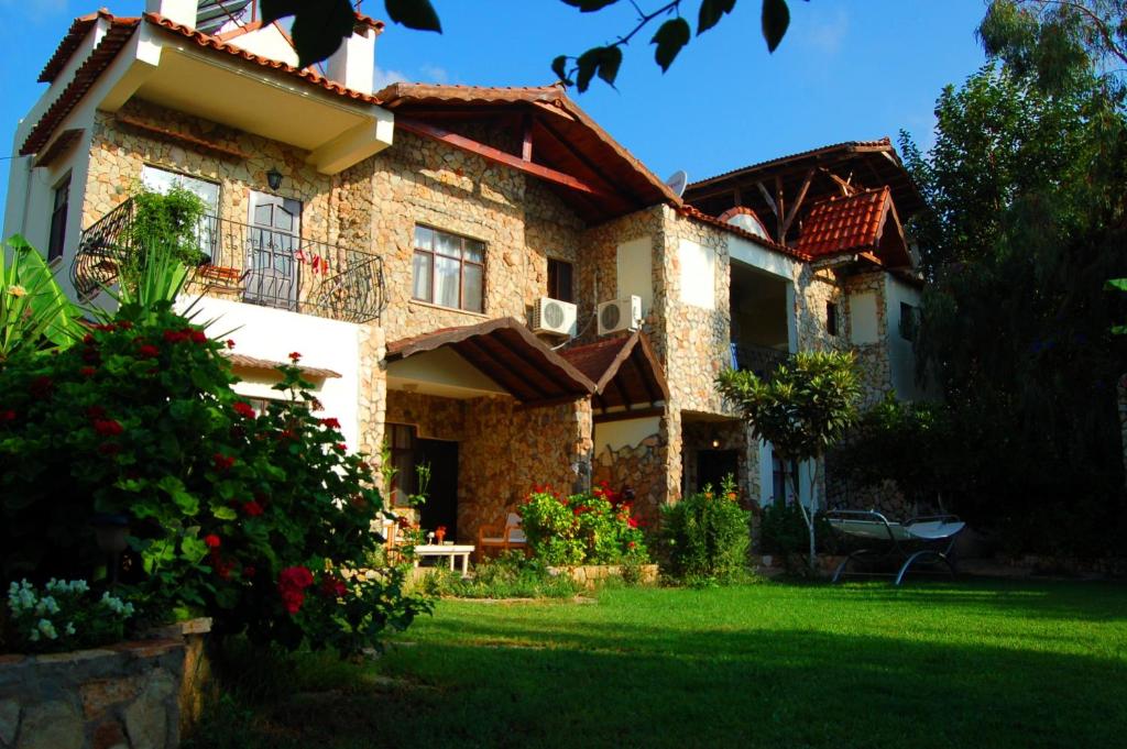 una casa con un césped verde delante de ella en Hotel Villa Monte en Cıralı