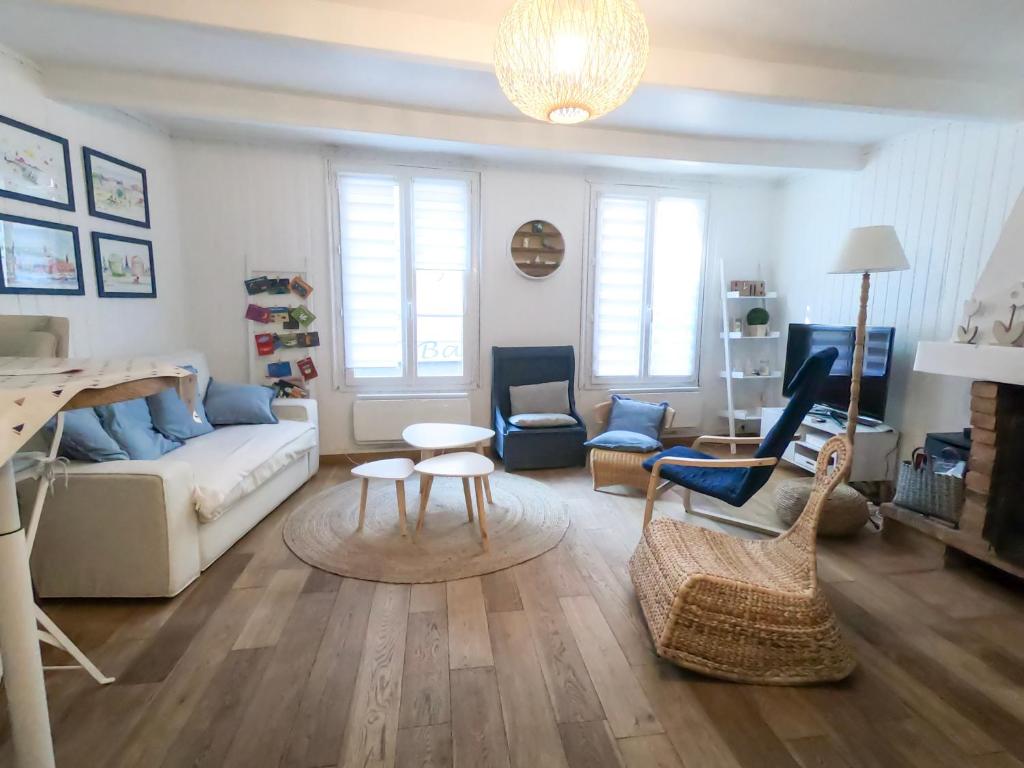 uma sala de estar com um sofá, uma mesa e cadeiras em La perle des Bains em Trouville-sur-Mer