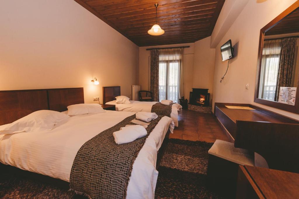 a hotel room with three beds and a television at Thea Mainalou in Vytina