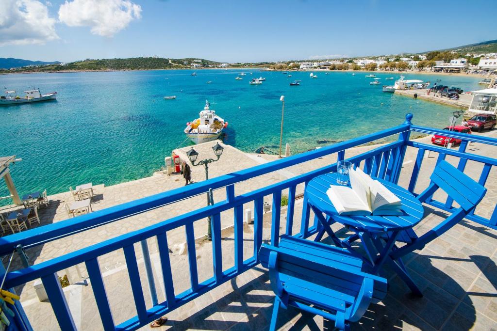 a couple of blue chairs on a balcony with a body of water at Angeliki Seaside Hotel in Aliki