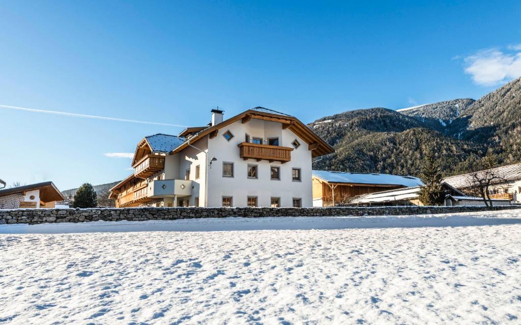 a house in the snow with mountains in the background at Christlrumerhof in Brunico