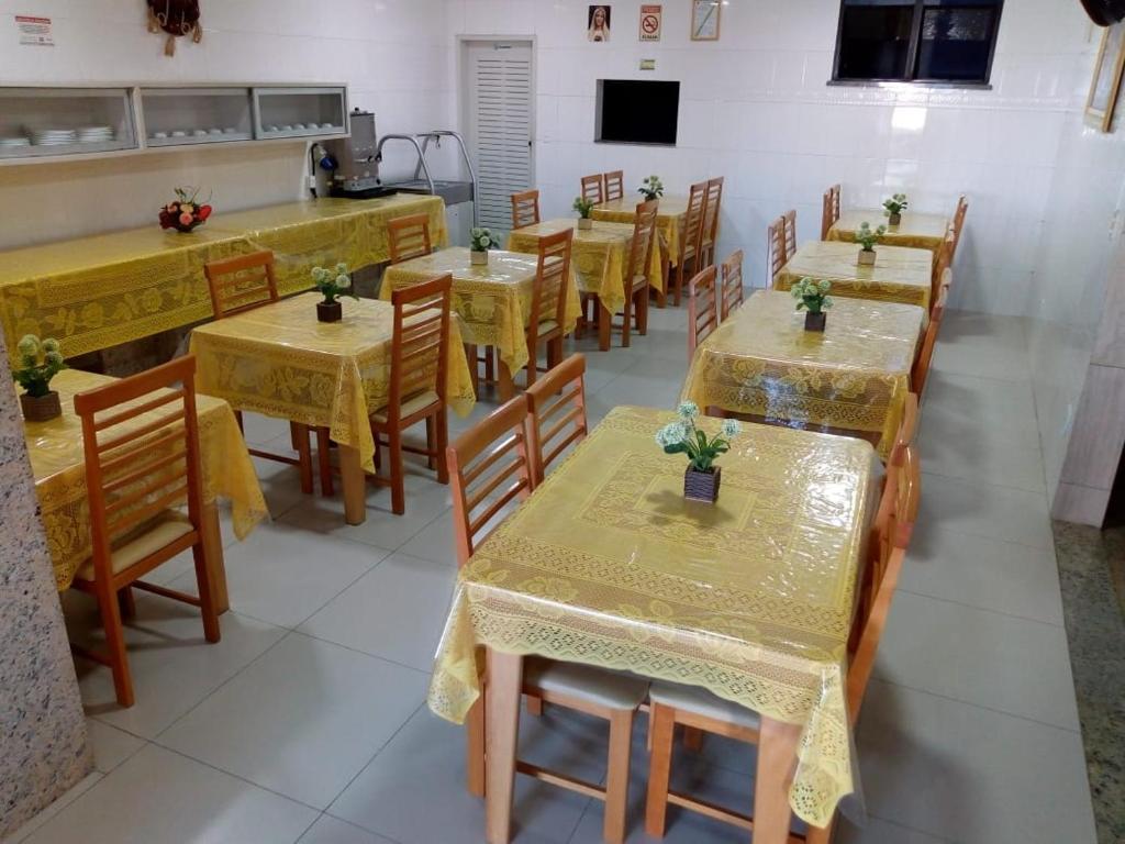 a dining room with tables and chairs with flowers on them at Hotel Praia e Mar in Aracaju