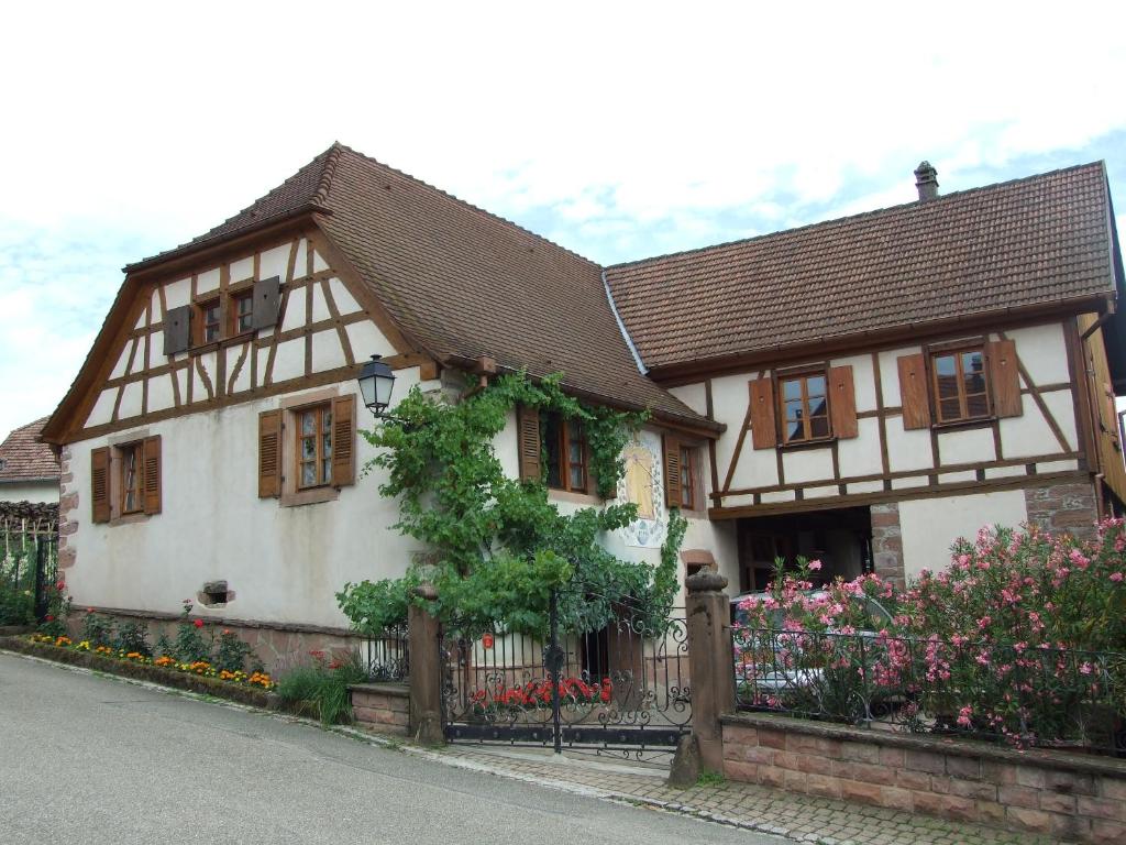 Triembach-au-ValにあるGîte "AU CADRAN SOLAIRE"の柵と花のある白と茶色の家