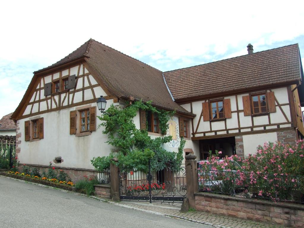 una casa bianca e marrone con recinzione e fiori di Gîte "AU CADRAN SOLAIRE" a Triembach-au-Val