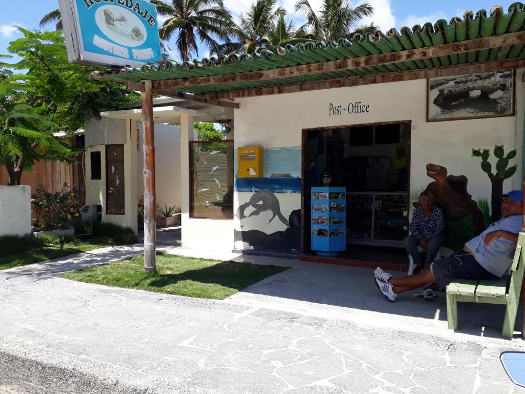een groep mensen die buiten een tankstation zitten bij Hospedaje Mother Fanny in Puerto Villamil