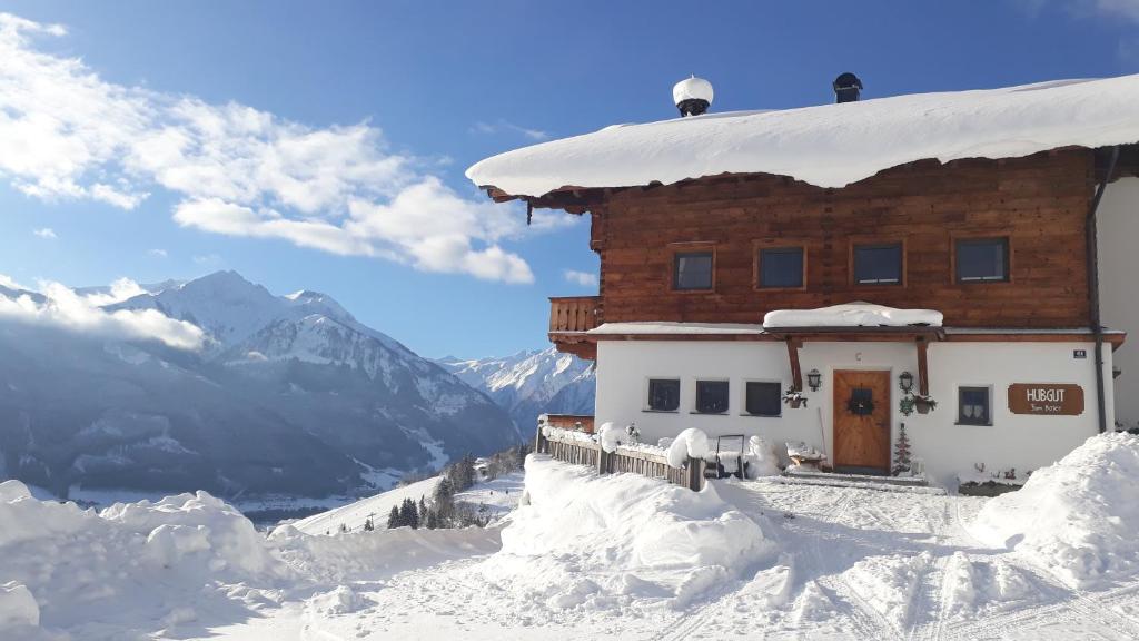 a building covered in snow with mountains in the background at Bio-Bergbauernhof Hubgut in Zell am See