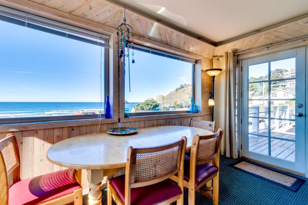 a dining room with a table and chairs and two windows at Wave Watch `N in Oceanside