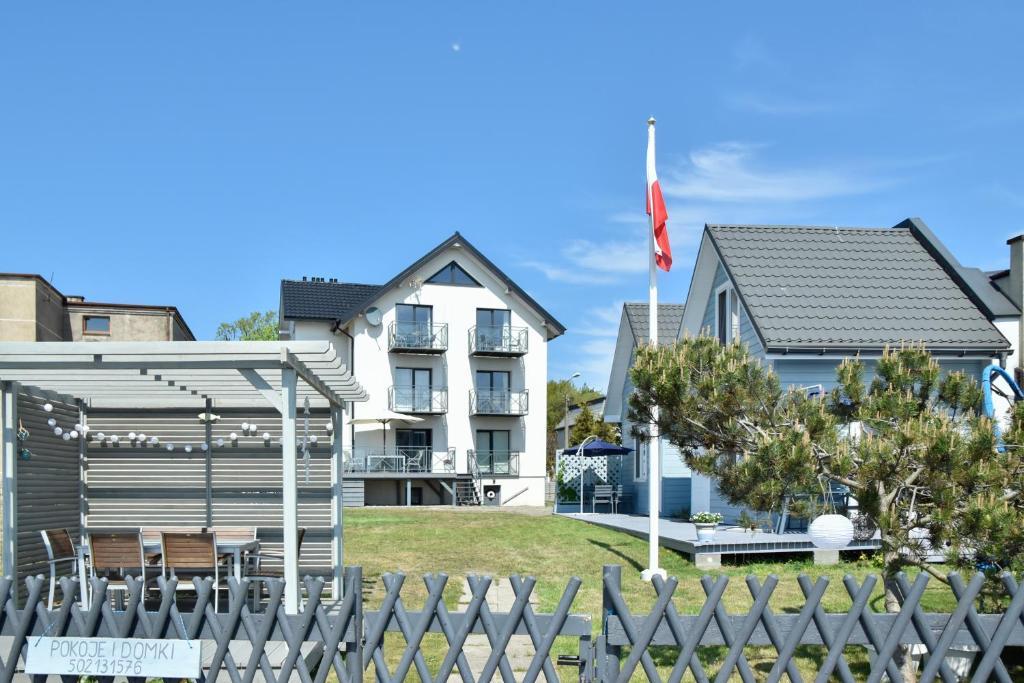 ein weißes Haus mit einer Flagge vor einem Zaun in der Unterkunft NORDA in Kuźnica