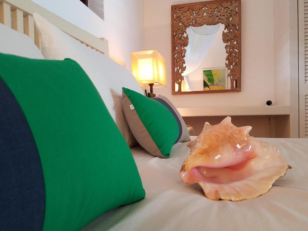 a seashell sitting on a bed with green pillows at Gingerbread Suites in Port Elizabeth