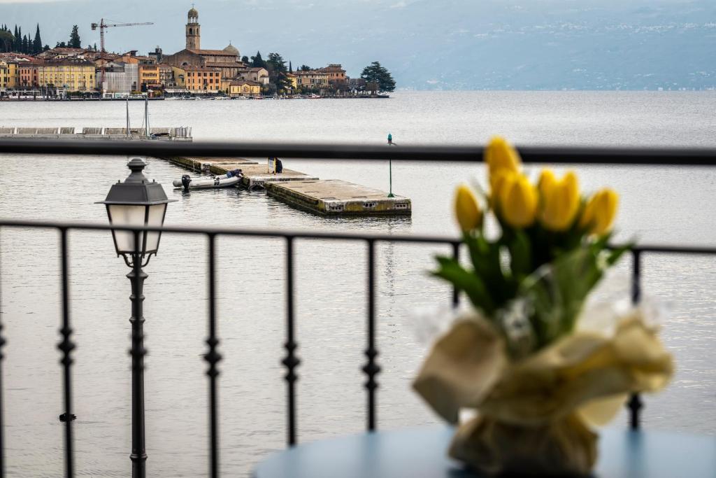 un vaso di fiori seduto su un tavolo accanto all'acqua di Casa Mari Fronte Lago a Salò