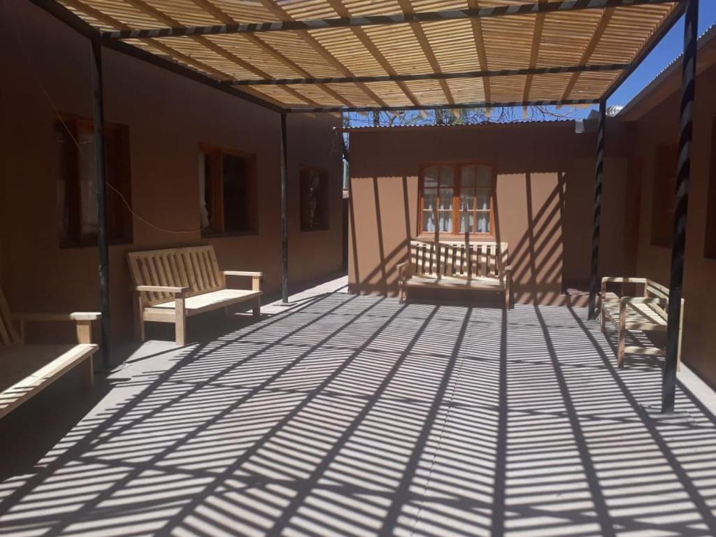 un porche con dos bancos y un sol brillando en él en CASA MACAW en San Pedro de Atacama