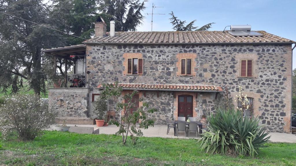 una antigua casa de piedra con un arbusto de piedra en B&B Il Cardellino en Porano