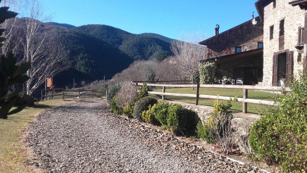 a gravel road next to a building with a fence at Cal Sadurní in Planoles