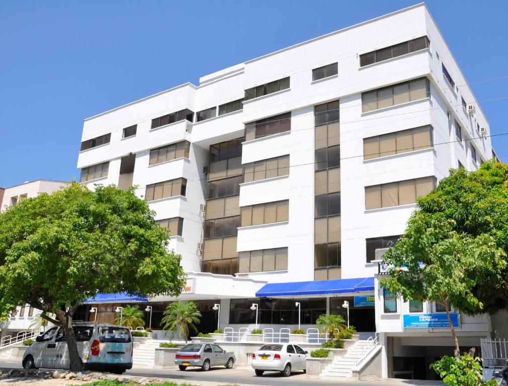 un edificio blanco con coches estacionados frente a él en Hotel Yuldama Rodadero Inn, en Santa Marta