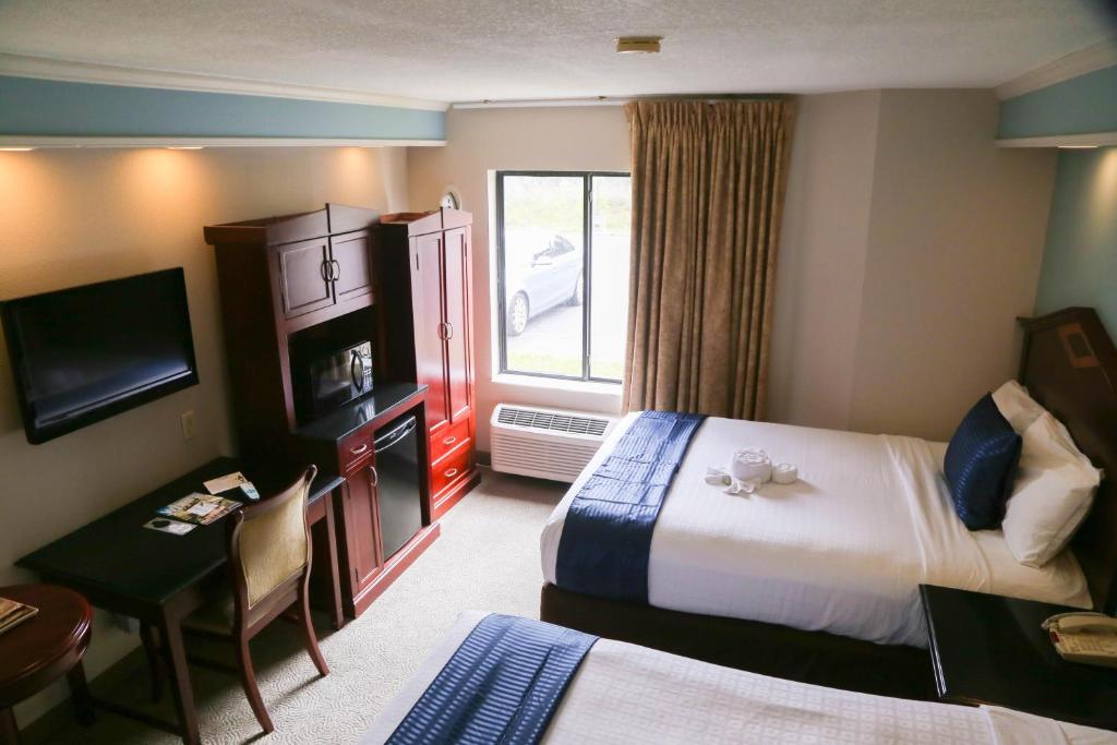 a hotel room with a bed and a desk and a room at Destiny Palms Hotel Maingate West in Kissimmee