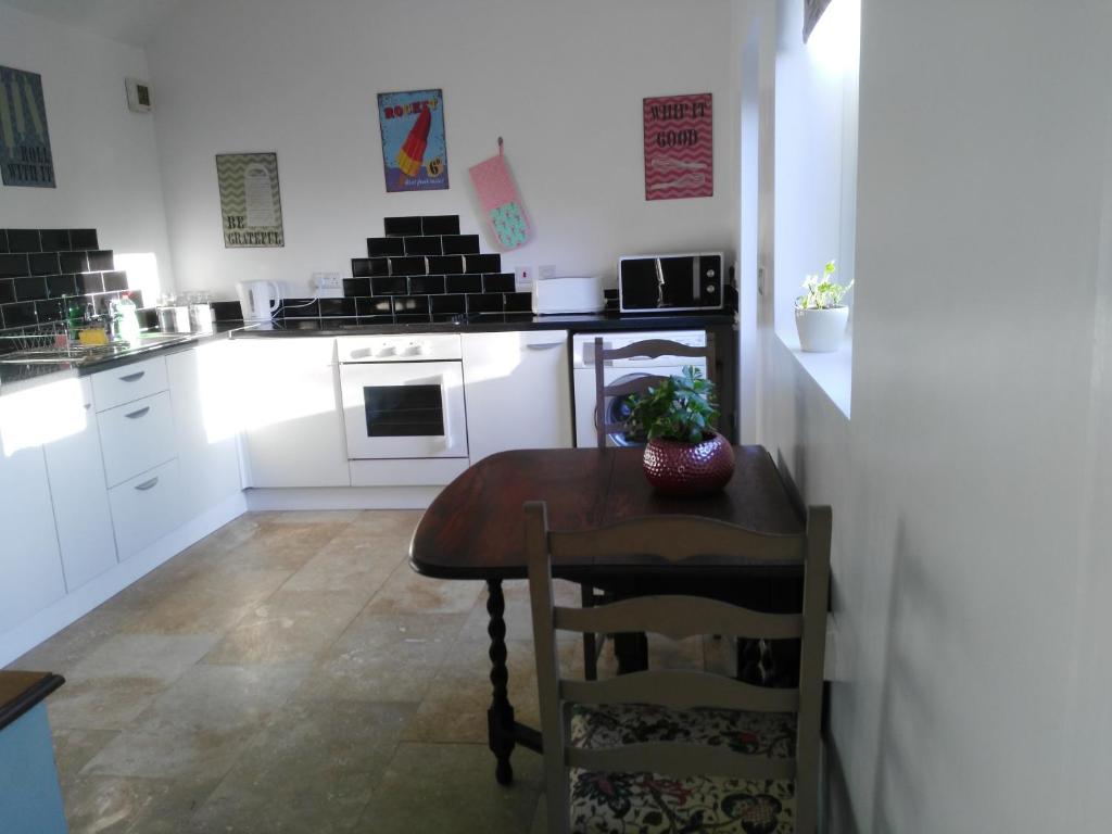 a small kitchen with a small table and a stove at Garden Cottage in Sleaford