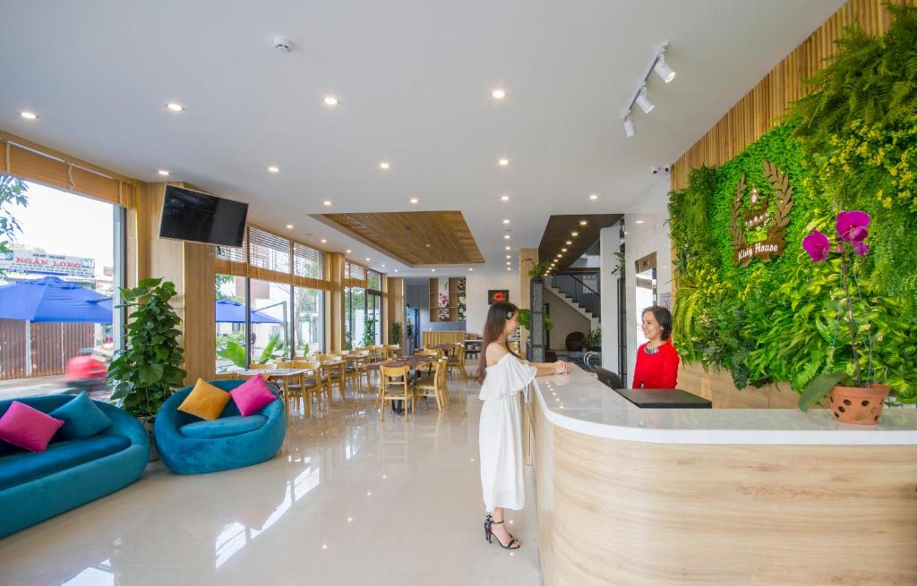 A polished reception lobby includes a curved check-in desk, lounge seating and a leafy feature wall.