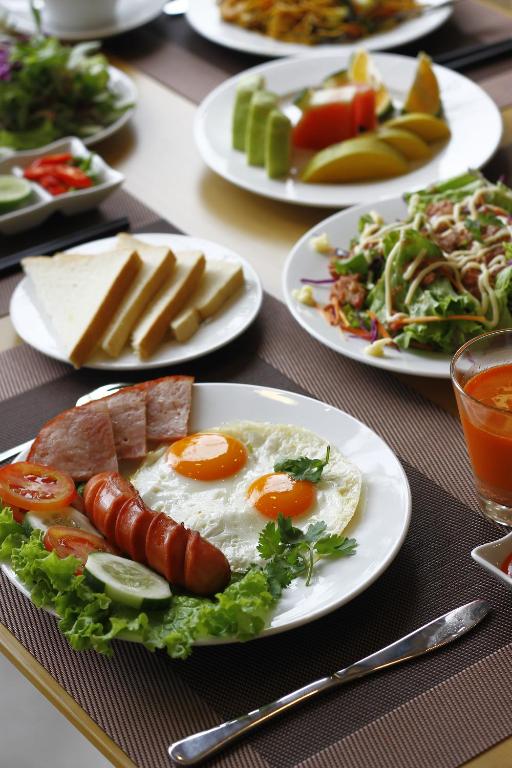 A plated breakfast spread with eggs, sausages, vegetables, fruit and bread.