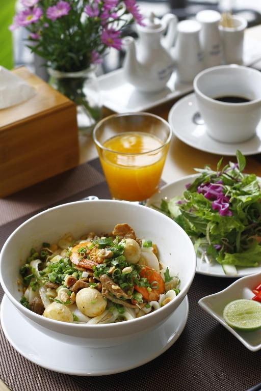 A Vietnamese-style noodle bowl served with salad, lime, juice, and coffee.