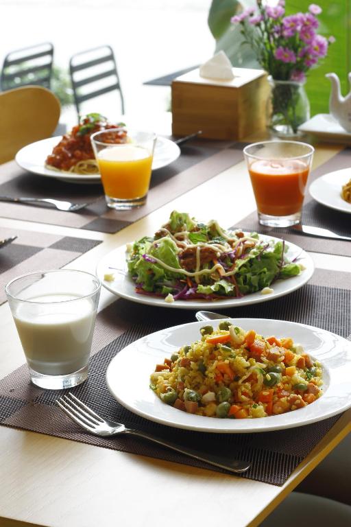 A breakfast table set with rice, salad, pasta, juice, and milk.