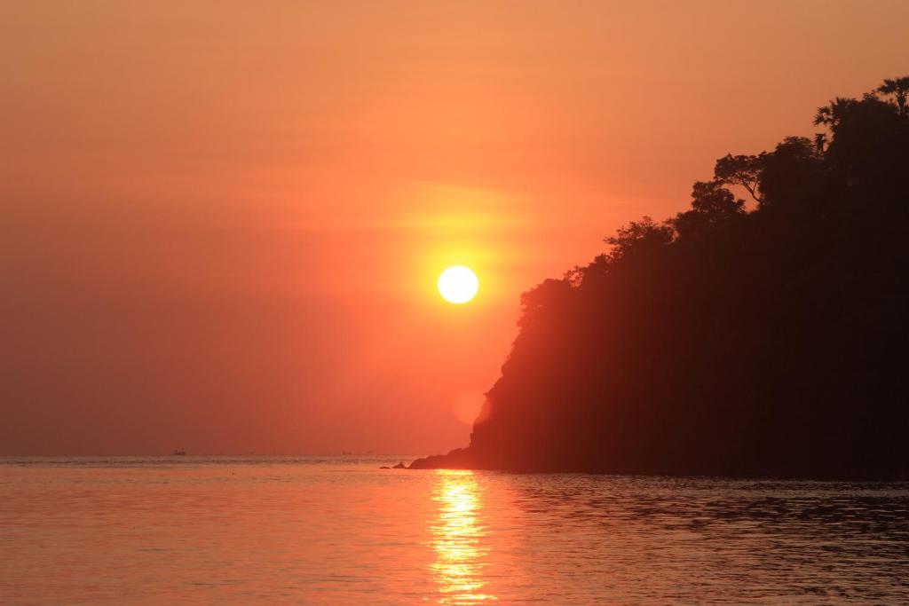 a sunset over a body of water with the sun setting at COCONUT BEACH BUNGALOWS & WARUNG Exst Teman-Teman 2 garden view in Amed