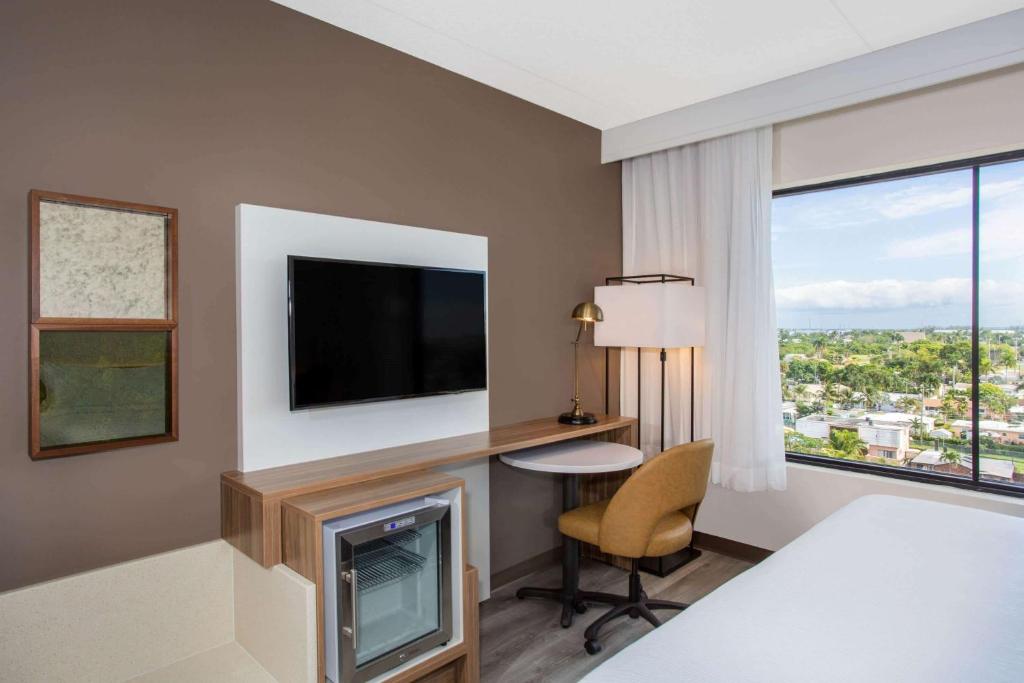 a hotel room with a tv and a desk with a chair at Wyndham Garden Ft Lauderdale Airport & Cruise Port in Dania Beach