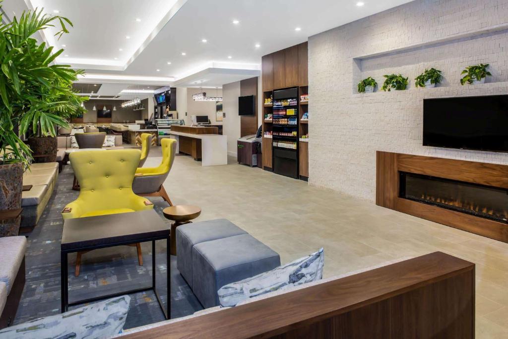 a lobby with a yellow chair and a fireplace at Wyndham Garden Ft Lauderdale Airport & Cruise Port in Dania Beach