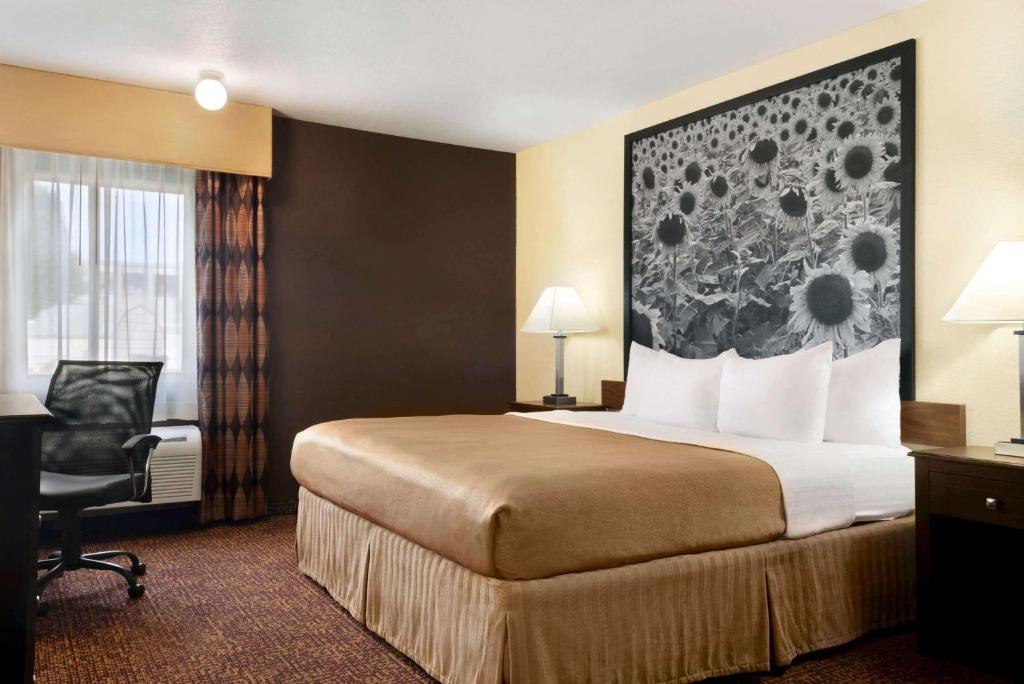 a hotel room with a bed and a desk and a chair at Super 8 by Wyndham Des Moines in Des Moines