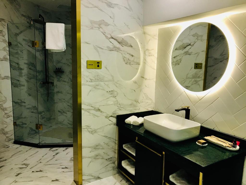 a bathroom with a sink and a shower with a mirror at Moon and Chalice Boutique Hotel in Kunming