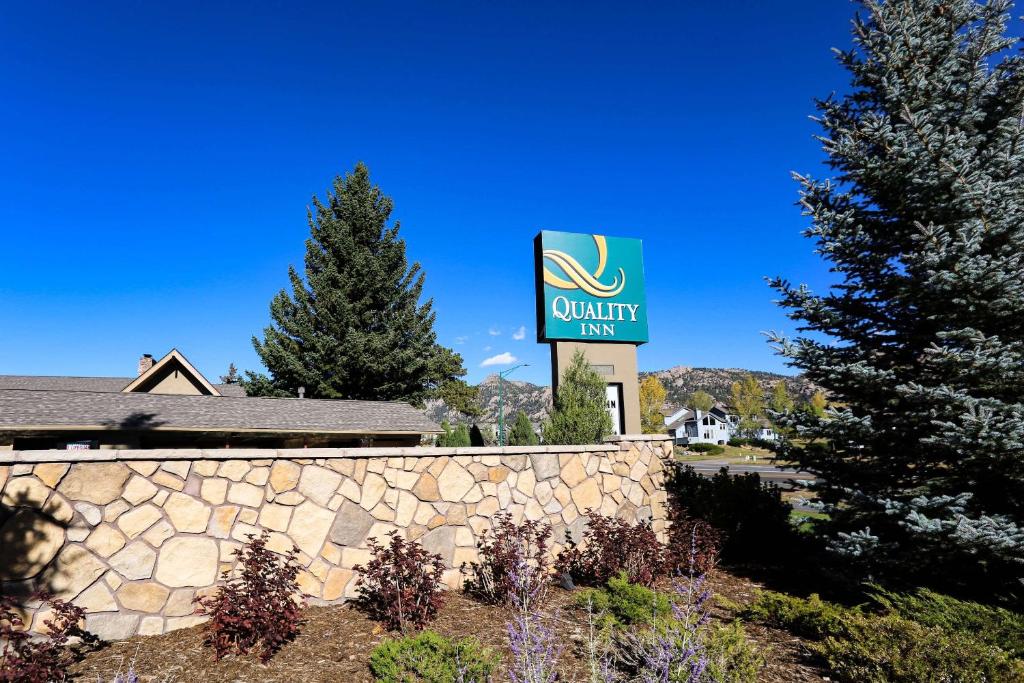 a sign for a quality inn next to a stone wall at Quality Inn near Rocky Mountain National Park in Estes Park