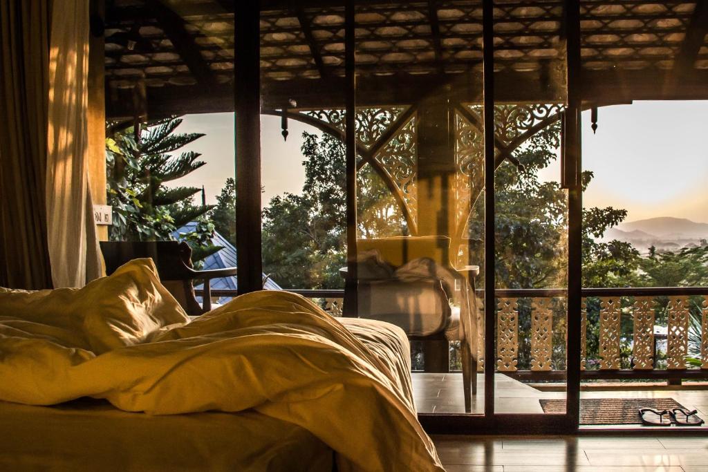 a bed in a room with a large window at Kongkarn Resort and Farmstay in Ban Pak Ngam