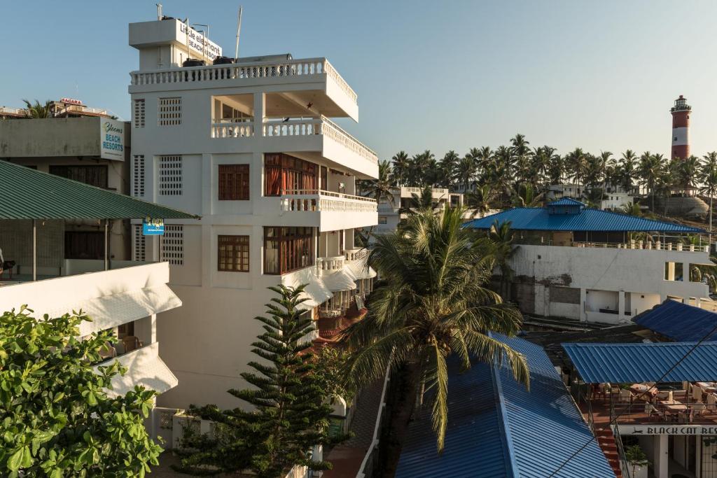 a white building with a palm tree in front of it at Little Elephant Beach Resort in Kovalam