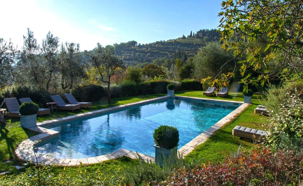 een zwembad in een tuin met stoelen en bomen bij Villa Bordoni in Greve in Chianti