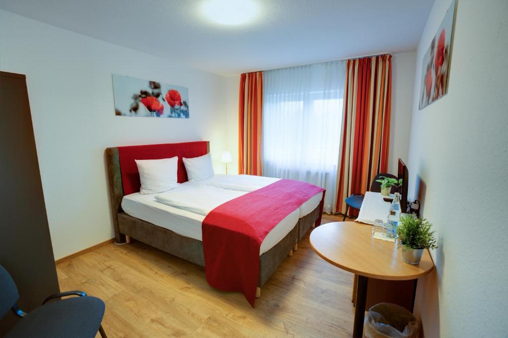 a hotel room with a bed and a table at Hotel Leo Mühlhausen in Mühlhausen