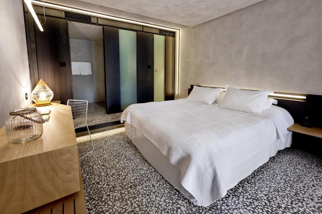 a bedroom with a large white bed and a table at Ekies All Senses Resort, a Member of Design Hotels in Vourvourou