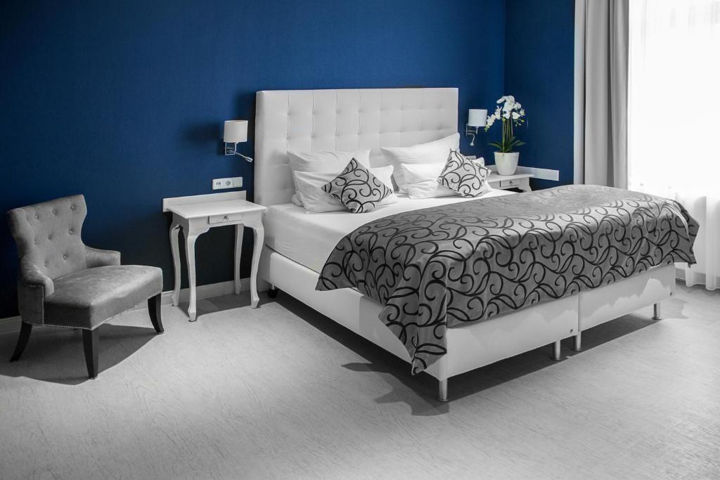 a blue bedroom with a bed and a chair at Haus Hotel & Pension Villa Laluna in Blankenburg