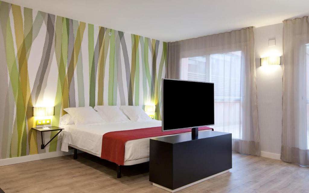 um quarto com uma cama e uma televisão de ecrã plano em Vértice Sevilla em Sevilha