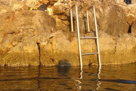 a ladder in the water next to a rock wall at Tramontana in Hydra