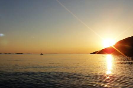 a sunset over a body of water with the sun setting at Tramontana in Hydra
