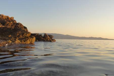 a body of water next to a rocky shore at Tramontana in Hydra