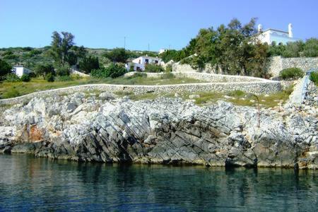 a rock wall next to a body of water at Tramontana in Hydra