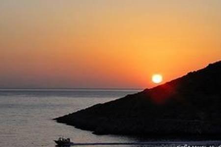 a sunset over the ocean with a boat in the water at Tramontana in Hydra
