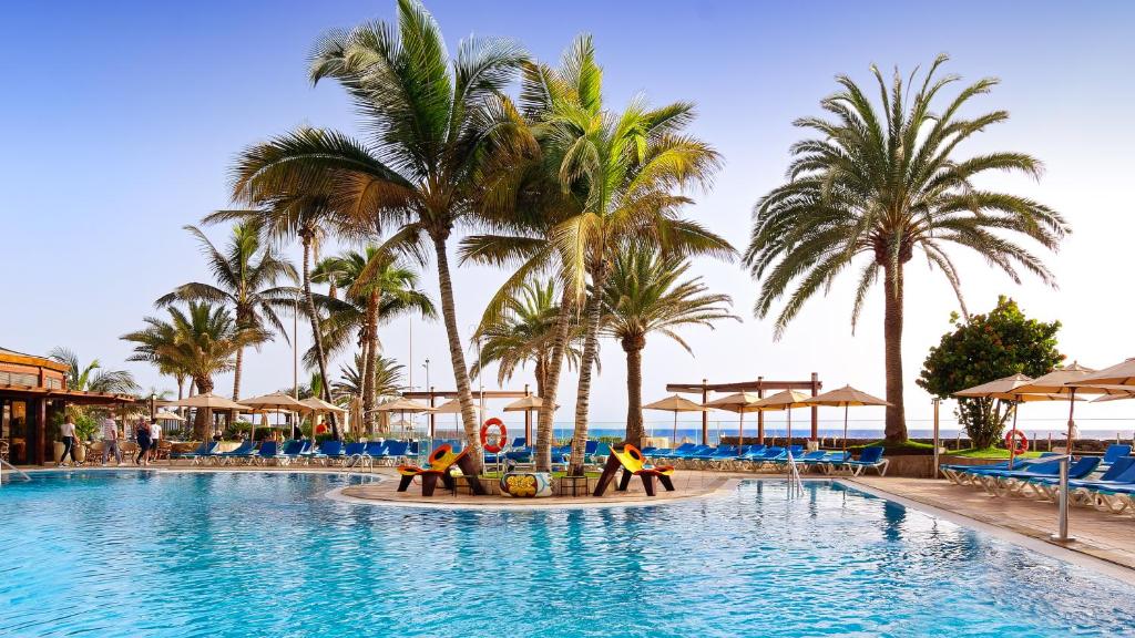 a swimming pool at a resort with palm trees at BULL Dorado Beach & SPA in La Playa de Arguineguín
